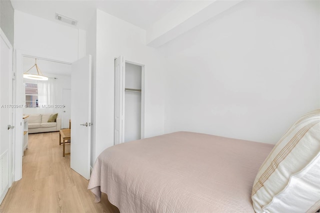 bedroom with light hardwood / wood-style floors and a closet