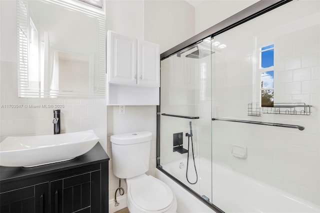 full bathroom with a wealth of natural light, toilet, shower / bath combination with glass door, decorative backsplash, and vanity