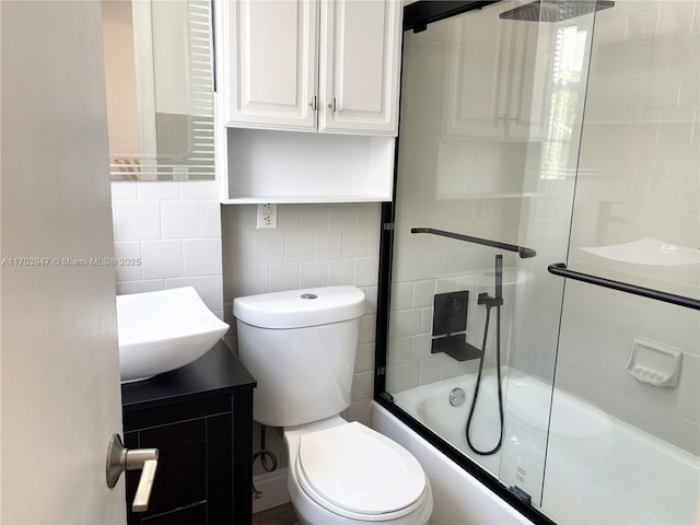 full bathroom featuring vanity, shower / bath combination with glass door, decorative backsplash, toilet, and tile walls