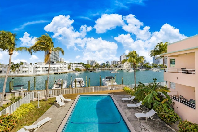 view of pool with a patio area, a water view, and a dock