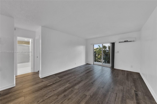 empty room featuring dark hardwood / wood-style flooring, an AC wall unit, and a textured ceiling