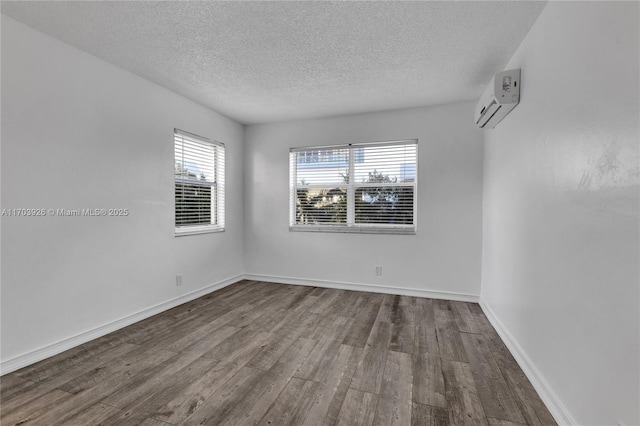 empty room featuring a wall mounted AC, hardwood / wood-style floors, and a textured ceiling