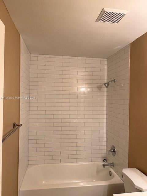 bathroom with tiled shower / bath combo and toilet