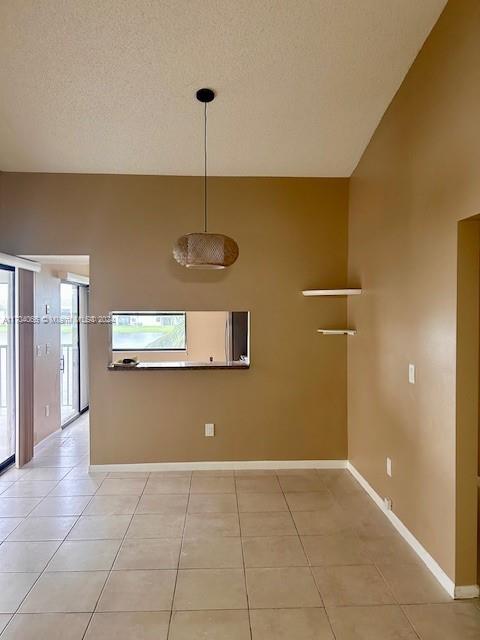 interior space with light tile patterned floors, a textured ceiling, and a high ceiling