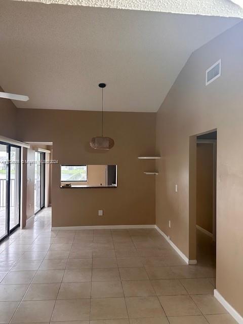 spare room with light tile patterned floors, a textured ceiling, and high vaulted ceiling