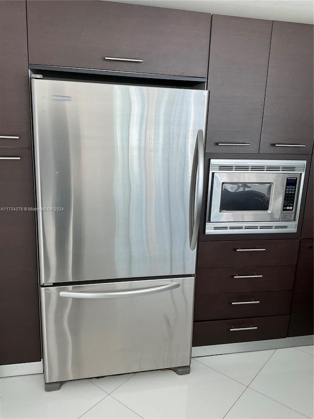 kitchen with dark brown cabinetry, light tile patterned floors, and stainless steel appliances