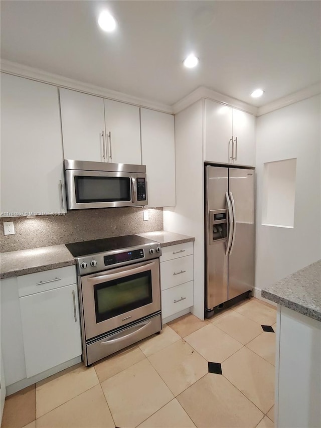 kitchen featuring white cabinetry, light stone countertops, tasteful backsplash, light tile patterned floors, and appliances with stainless steel finishes