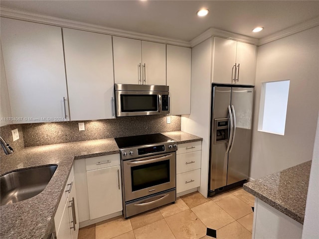 kitchen featuring sink, crown molding, dark stone counters, white cabinets, and appliances with stainless steel finishes