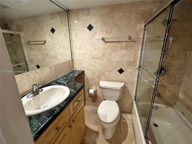 full bathroom with vanity, tile patterned flooring, toilet, enclosed tub / shower combo, and tile walls