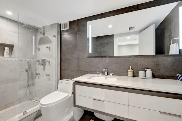 bathroom with backsplash, vanity, tiled shower, tile walls, and toilet