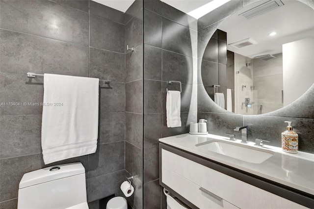 bathroom featuring vanity, decorative backsplash, toilet, tile walls, and a tile shower