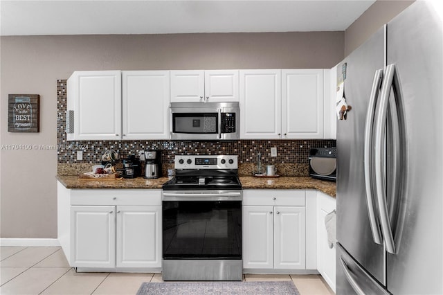 kitchen featuring stainless steel appliances, white cabinetry, tasteful backsplash, and dark stone counters