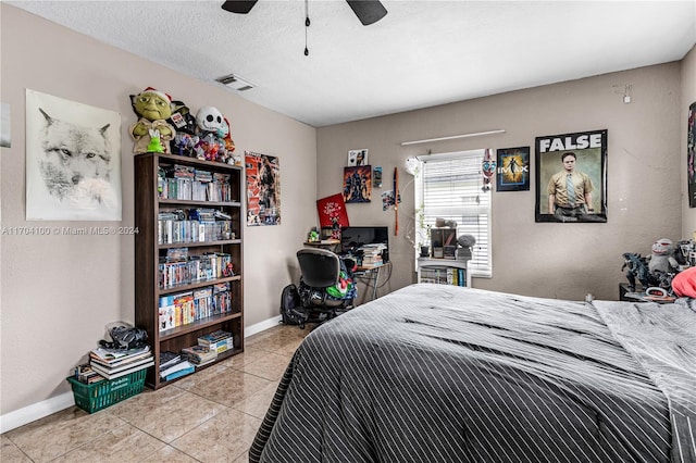 bedroom featuring ceiling fan, light tile patterned flooring, and a textured ceiling