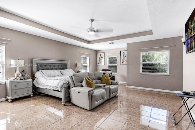 tiled bedroom featuring a tray ceiling and ceiling fan