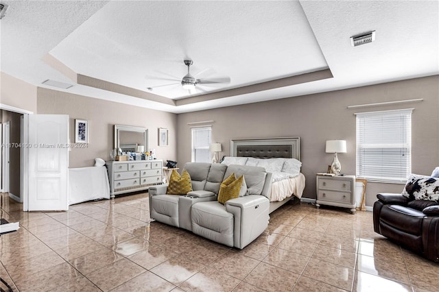 tiled bedroom featuring a textured ceiling, a tray ceiling, and ceiling fan