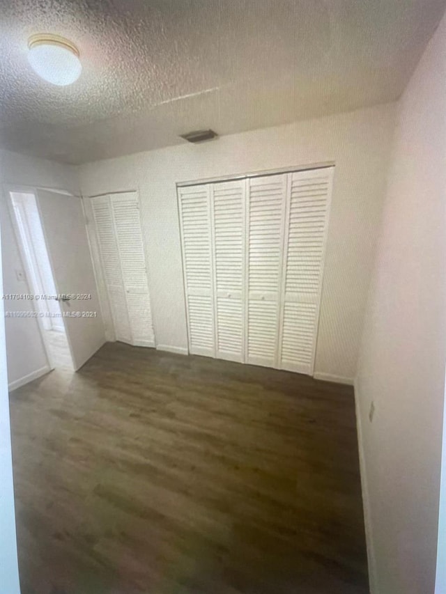 unfurnished bedroom with dark hardwood / wood-style flooring and a textured ceiling