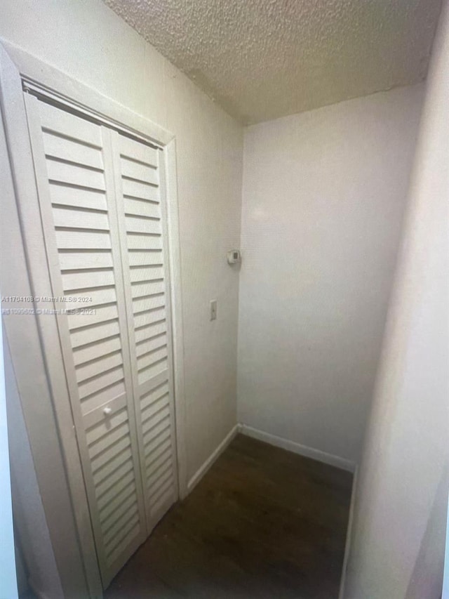 hallway with dark hardwood / wood-style flooring and a textured ceiling