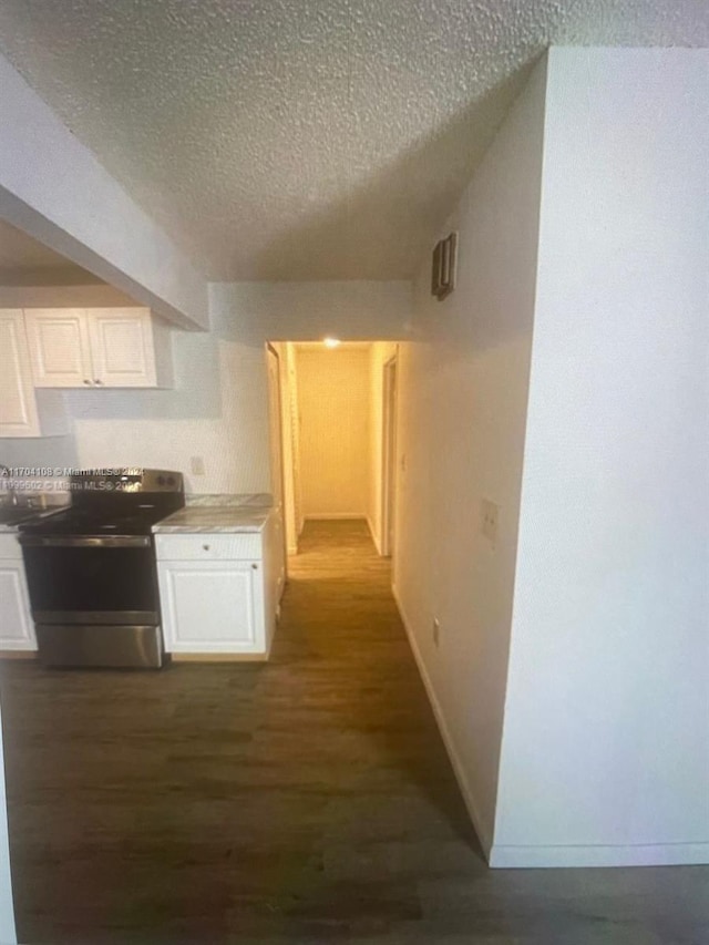 hallway featuring a textured ceiling, dark wood-type flooring, and vaulted ceiling