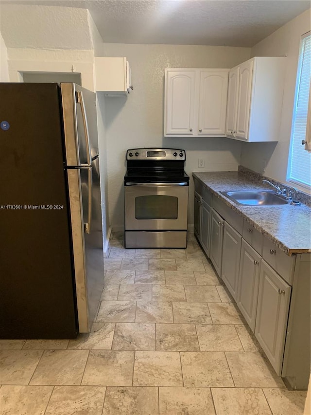 kitchen featuring a wealth of natural light, white cabinetry, sink, and appliances with stainless steel finishes