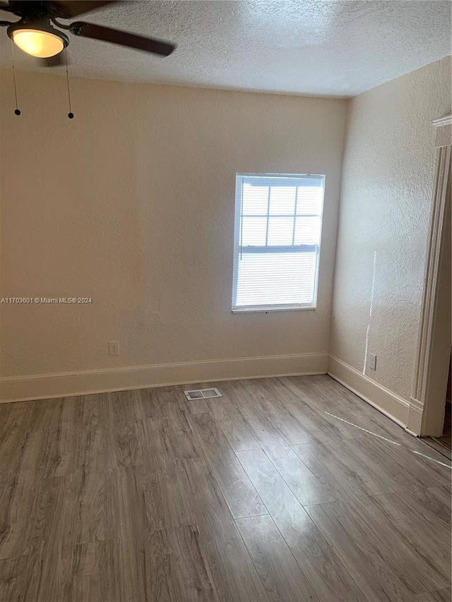 spare room with hardwood / wood-style floors, a textured ceiling, and ceiling fan