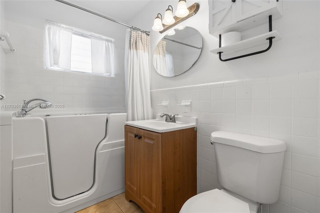 bathroom featuring a shower with shower curtain, tile patterned floors, vanity, tile walls, and toilet