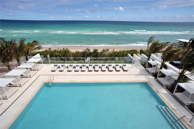 view of swimming pool with a view of the beach, a water view, and a patio area