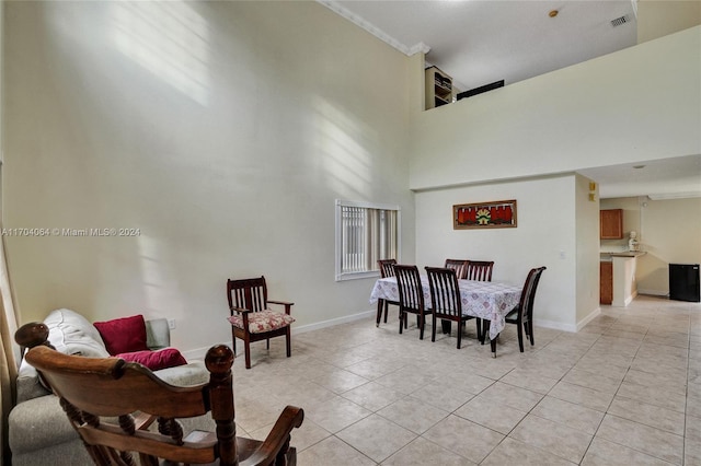 dining room with a towering ceiling, crown molding, and light tile patterned flooring