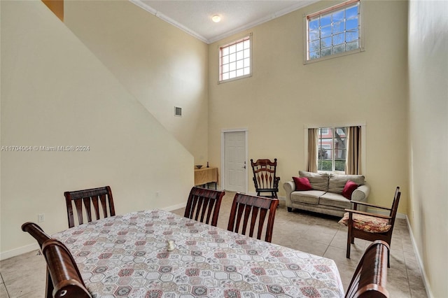 tiled dining space with a high ceiling, plenty of natural light, and crown molding