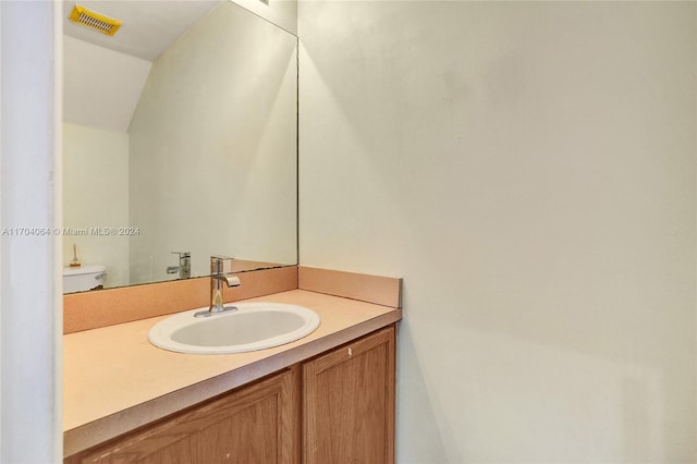 bathroom with vanity, toilet, and vaulted ceiling