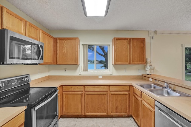 kitchen with light tile patterned flooring, sink, a textured ceiling, and appliances with stainless steel finishes