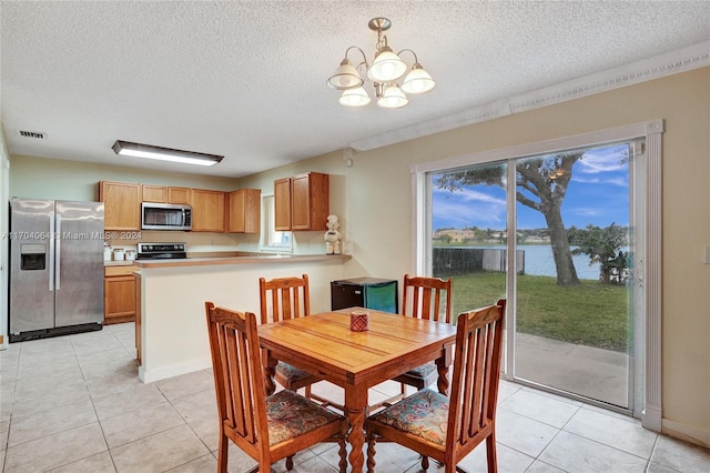 dining area featuring a water view, light tile patterned flooring, a textured ceiling, and an inviting chandelier