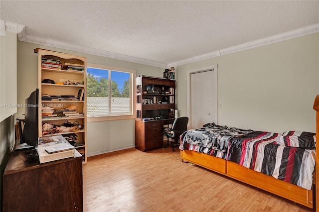 bedroom with a textured ceiling, light hardwood / wood-style flooring, and ornamental molding