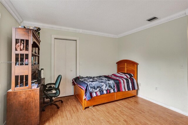 bedroom featuring hardwood / wood-style floors, ornamental molding, and a textured ceiling