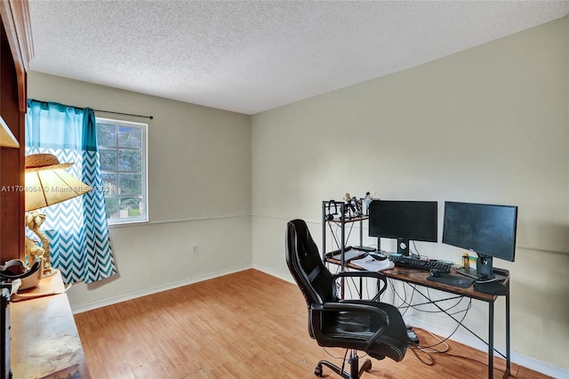 home office with a textured ceiling and light hardwood / wood-style flooring