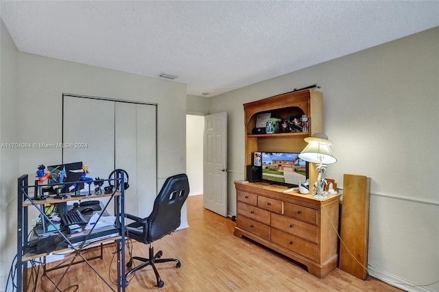 office area with light wood-type flooring and a textured ceiling