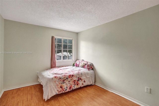 bedroom with wood-type flooring and a textured ceiling