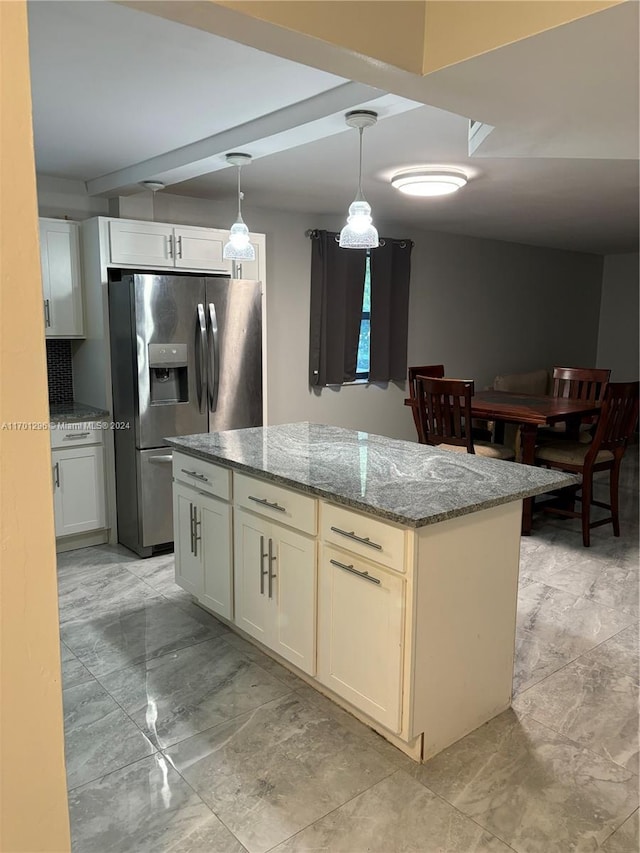 kitchen featuring pendant lighting, a center island, stainless steel fridge, light stone counters, and white cabinetry