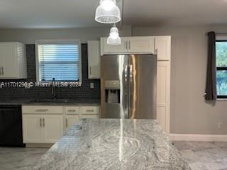 kitchen featuring white cabinets, stainless steel fridge, light stone counters, and dishwasher