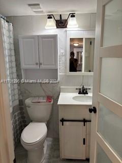 bathroom featuring a shower with shower curtain, vanity, and toilet