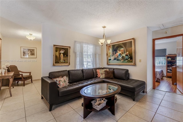 tiled living room featuring a textured ceiling and a notable chandelier