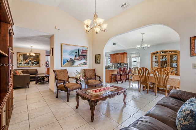 living room featuring a chandelier, light tile patterned floors, and lofted ceiling