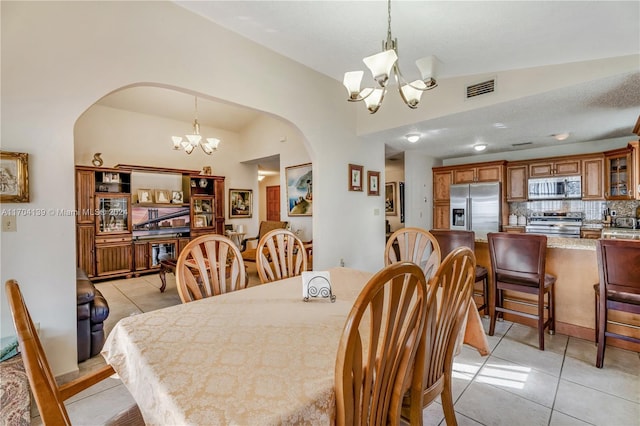 dining room with light tile patterned floors, lofted ceiling, and a notable chandelier