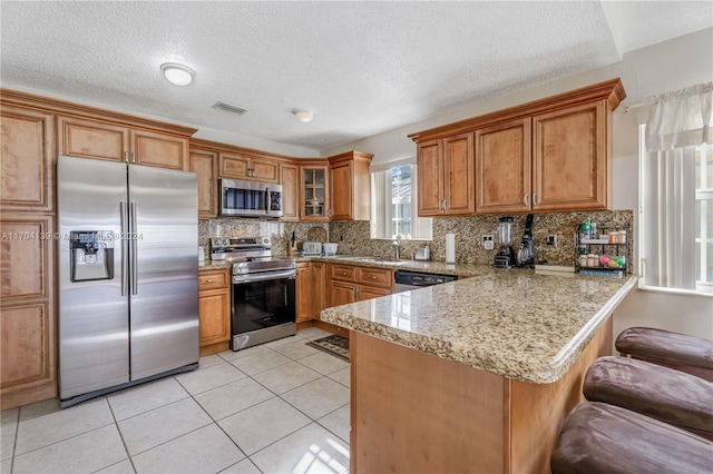 kitchen with kitchen peninsula, a textured ceiling, and stainless steel appliances