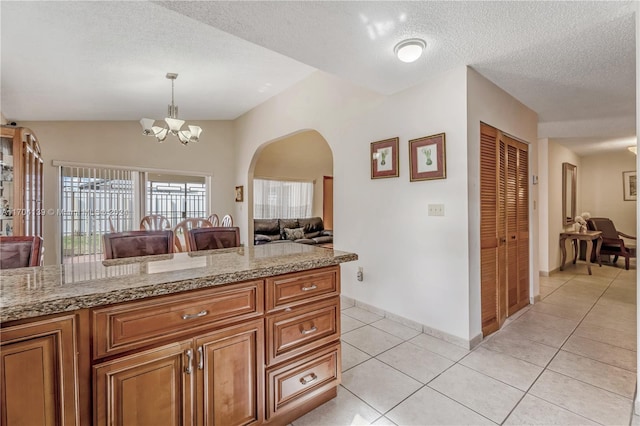 kitchen featuring a chandelier, a textured ceiling, decorative light fixtures, and light tile patterned flooring