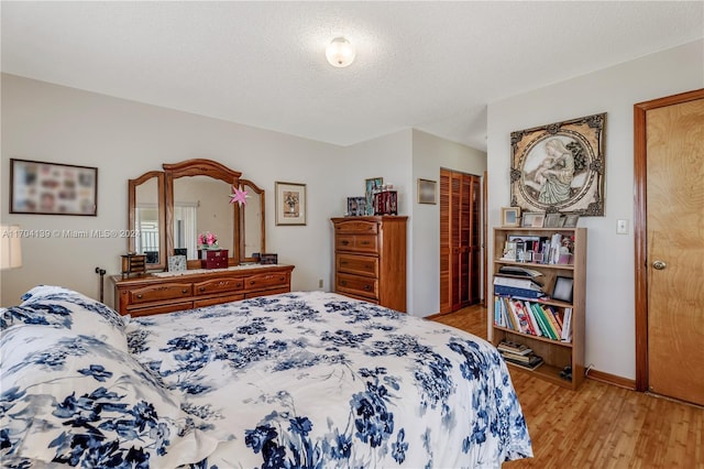 bedroom with a textured ceiling and light hardwood / wood-style flooring