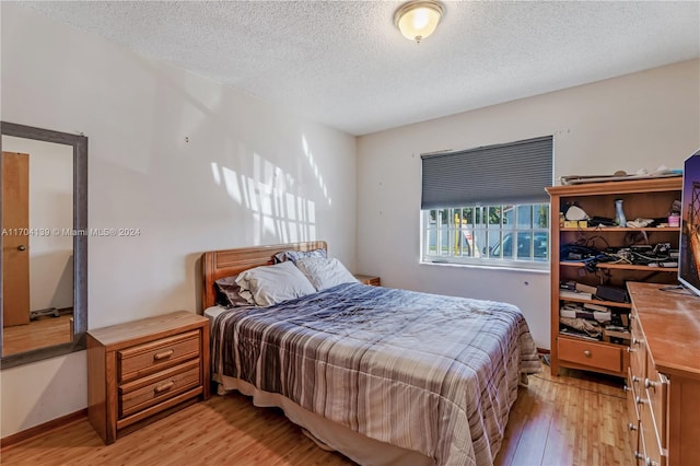 bedroom with light hardwood / wood-style flooring and a textured ceiling