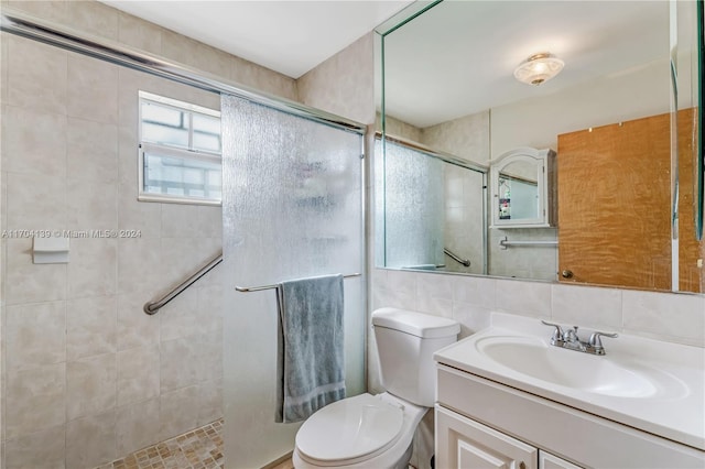 bathroom with vanity, a shower with door, decorative backsplash, toilet, and tile walls