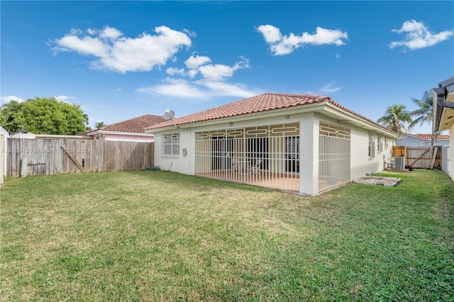 back of house featuring central AC unit and a yard