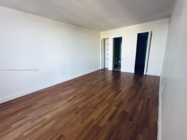 empty room with a textured ceiling and dark hardwood / wood-style floors