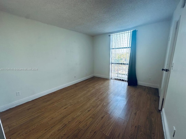 unfurnished room featuring a textured ceiling and dark wood-type flooring